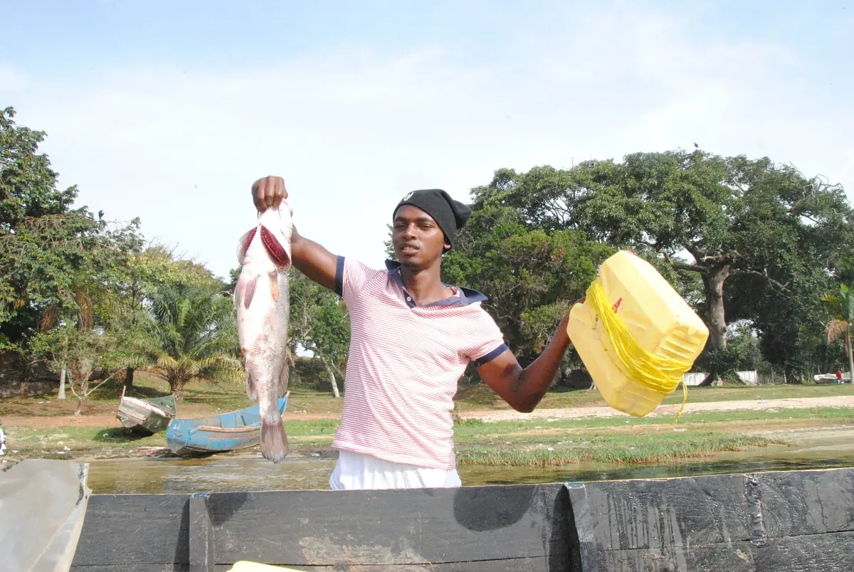 A fisherman holding up a fish caught on Lake Victoria